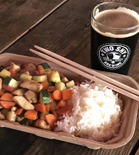 A photo of a delicious HuNan Chinese Gong Bao Chicken dish and a glass of beer from Two Shy Brewing in Roseburg, OR